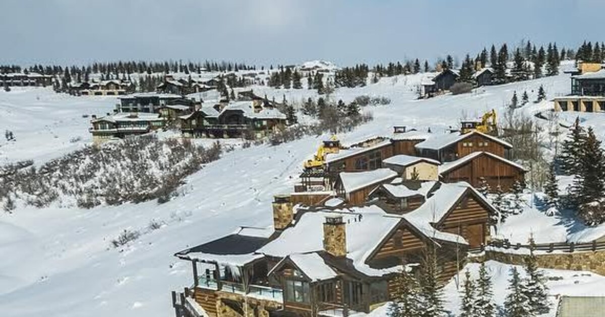 Snow-covered hillside homes with a yellow excavator in the middle distance